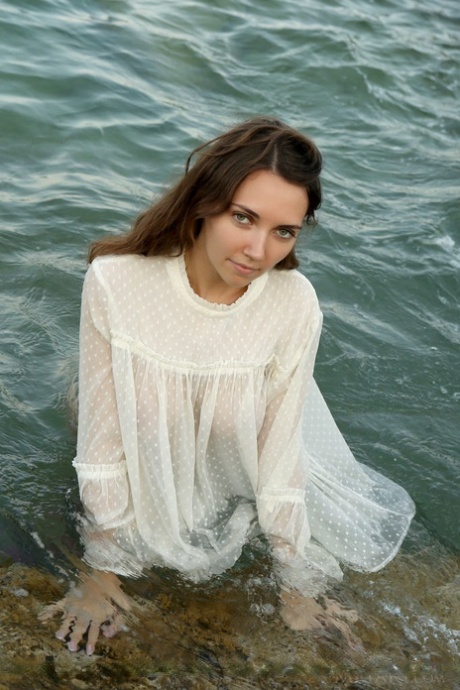 Teen solo girl Danniela frees nice tits from wet clothing on a sea shelf