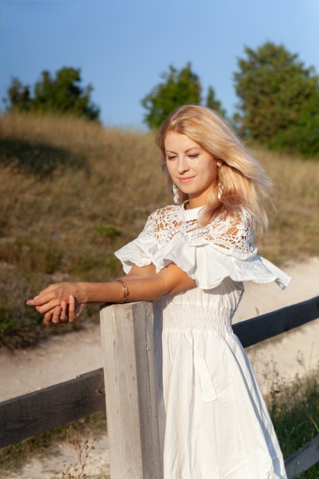 Sweet blonde teen Claire removes her dress to go nude against a rural fence