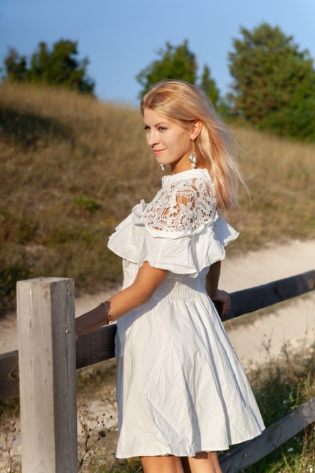 Sweet blonde teen Claire removes her dress to go nude against a rural fence