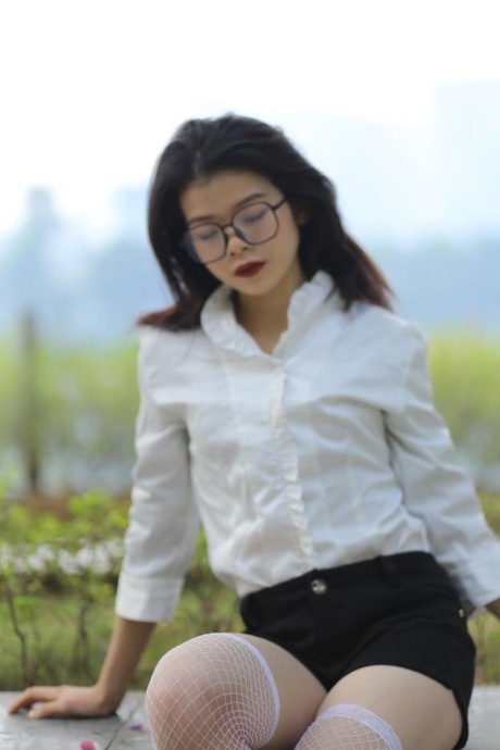 Dark-haired Asian model Irina posing in her lovely outfit outdoors
